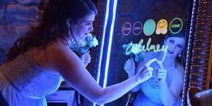 A bride gaze at a mirror adorned with a decorative sign, capturing a moment of reflection on their special day.