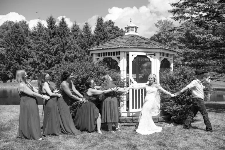 Black-and-white wedding party photograph beside a garden gazebo